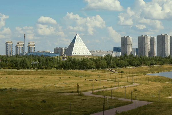 shore of the yesil river in astana with the palace of peace and reconciliation in the background