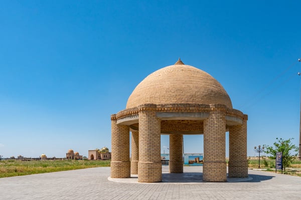 turkestan arystan bab mausoleum pavilion with golden cupola mausoleums at background on a sunny blue