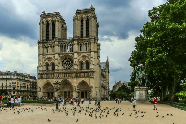 view on notre dame of paris france from square with pigeons and tourists 